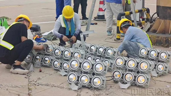 Technicians assembling LED high-mast floodlight modules at ground level